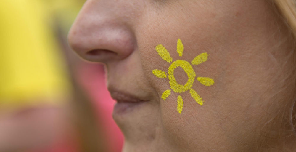 A Dianne Oxberry Trust supporter with the sunshine logo painted on their cheek